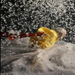 In einer ikonischen Szene aus Slavas Schneeshow kämpft ein in Gelb gekleideter Clown gegen einen gewaltigen Schneesturm und Konfetti.