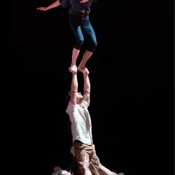 Een artiest balanceert op de handen van een acrobaat, gedragen door het hele collectief in een indrukwekkende menselijke piramide tijdens de voorstelling 'Wachten op de grote avond'.