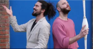 Portret van de kunstenaars Paul-Emmanuel Chevalley en Félix Didou voor een blauwe achtergrond; de een is een jongleur en danser, de ander een jongleur en goochelaar met een jongleerknuppel.