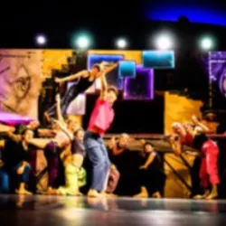 Studenten van het Tremplin-trainingsprogramma van het Balthazar Circus Arts Centre creëren een gezamenlijk stuk waarin acrobatische lifts, acteerwerk en podiumexpressie samenkomen op een kleurrijk podium.