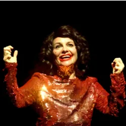 Portrait of Camille Weiss in a sparkling red costume on stage, smiling under a spotlight, illustrating a professional workshop dedicated to writing and creating clown shows.