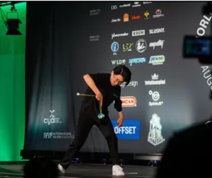 Competitor performing a yo-yo trick on stage at the World Yo-Yo Contest 2026 in front of official sponsors in Himeji, Japan.