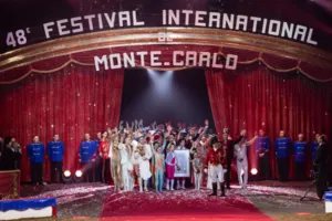 Photograph of the closing ceremony of the 48th Monte-Carlo International Circus Festival. The award-winning artists are gathered in the ring under an arch bearing the inscription "48th Monte-Carlo International Circus Festival". Confetti