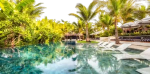 Main swimming pool of the tropical resort housing the Hoop Dream Retreat, surrounded by palm trees, lush vegetation and relaxation areas.