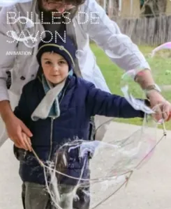 A young child participates in a science workshop about soap bubbles with an instructor wearing a white lab coat. The child manipulates a large frame to create a huge soap bubble. The title "Soap Bubbles - Animation" appears.