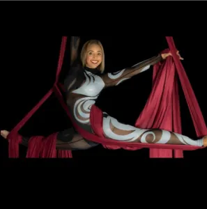 Artiste aérienne réalisant une figure en grand écart dans un tissu aérien rouge sur fond noir, visuel illustrant le stage international de cirque aérien World Dance Movement Italy.