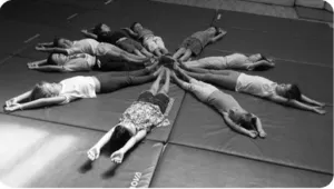 Groupe d’enfants allongés en cercle sur des tapis de gymnastique lors d’une activité collective à l’École de cirque Ballabulle de Biarritz.