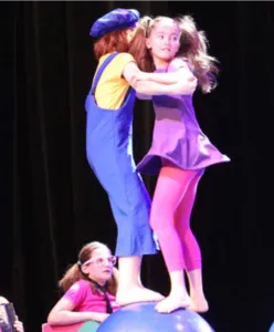 Enfants de l’École de Cirque Flip Flap Circus réalisant un numéro d’équilibre sur une boule de cirque, illustration des stages de cirque pour les 6-14 ans organisés à Paris.