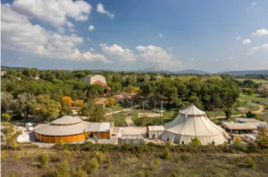 Vue aérienne du Centre International des Arts en Mouvement à Aix-en-Provence, avec les chapiteaux du CIAM entourés de végétation et la montagne Sainte-Victoire à l’horizon.