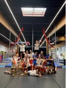 Groupe d’enfants et d’adolescents dans la salle de Cirqu’Onflexe à Amiens, équipée de tapis et d’agrès aériens pour les stages et ateliers d’arts du cirque.